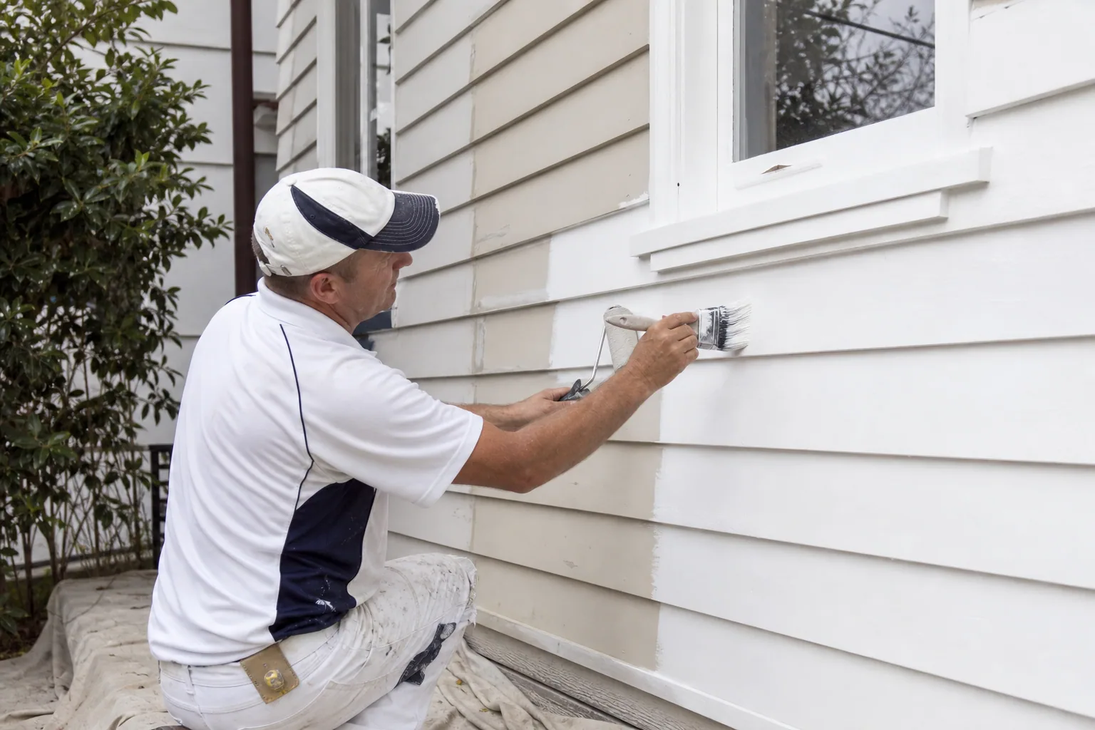 Painter brushing prepared timber weatherboards